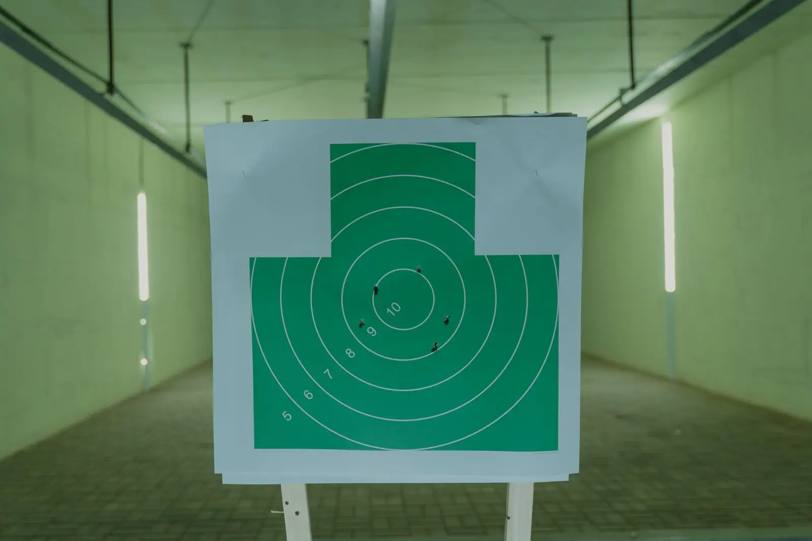 Green circular target with bullet holes at an indoor range